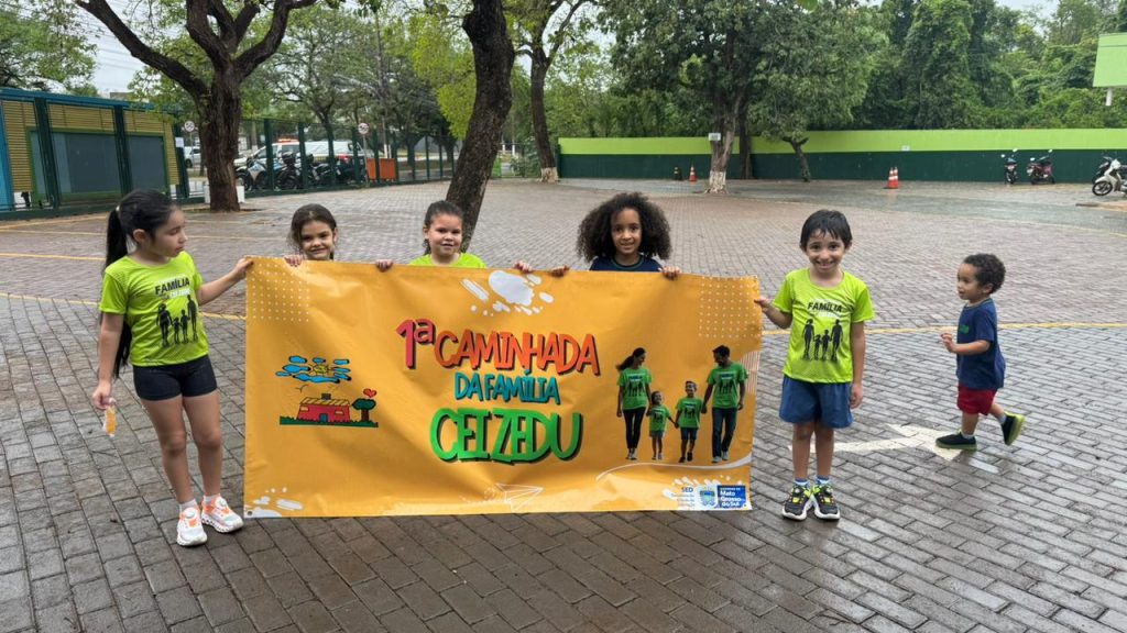 Duas crianças segurando uma faixa escrito 1ª caminhada da família CEI ZEDU.