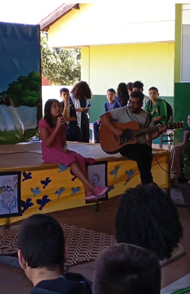 estudante cantando ao lado do professoro tocando violão.