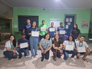 Professores e estudantes posando para foto na escola com medalhas e menções honrosas.