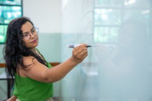 Imagem destacada de Professora escrevendo na lousa.