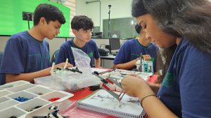 Caroline e outros estudantes com a peças do kit robótica.